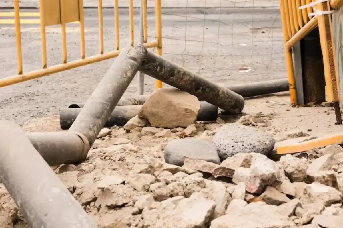 Cracked and collapsed sewer pipe sections lying in disturbed soil